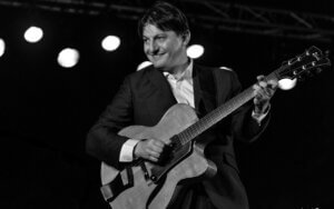 Hugo Lippi sur scène avec une guitare.